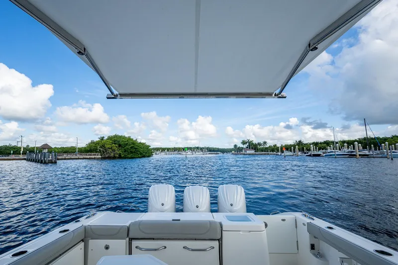  Yacht Photos Pics 2022 Pursuit OS 355 Offshore boat with scenic marina view under a clear sky.
