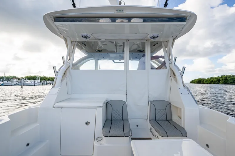  Yacht Photos Pics 2022 Pursuit OS 355 Offshore boat interior with seating, on a calm waterway.