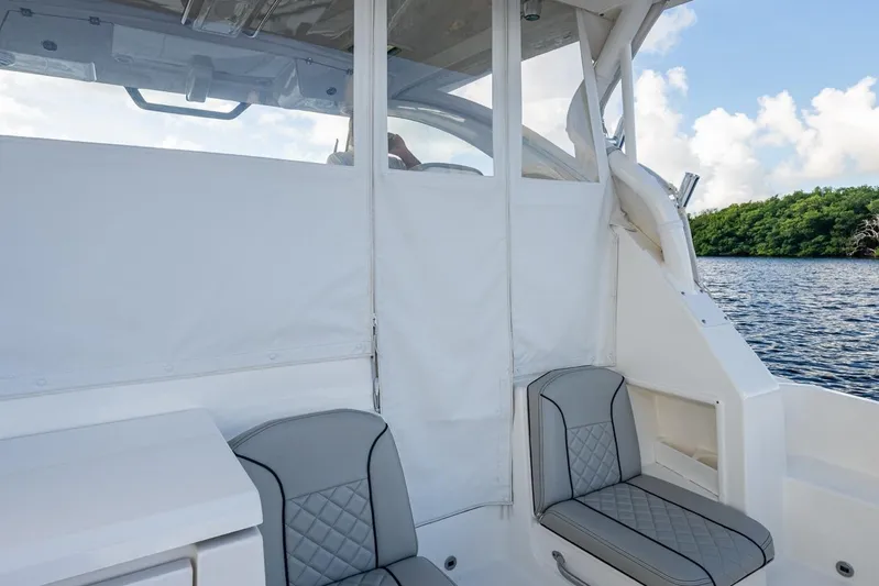  Yacht Photos Pics 2022 Pursuit OS 355 Offshore boat interior with seating, near water and greenery.