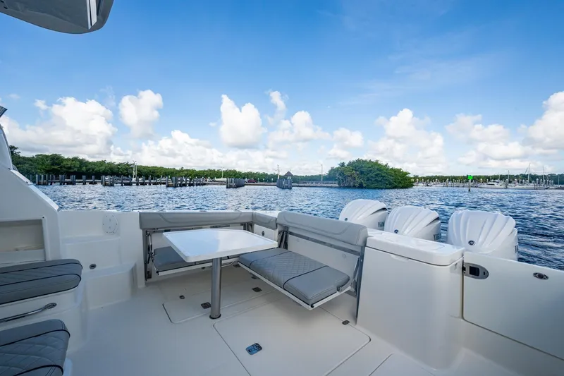  Yacht Photos Pics 2022 Pursuit OS 355 Offshore boat interior with seating and table, overlooking serene water and sky.