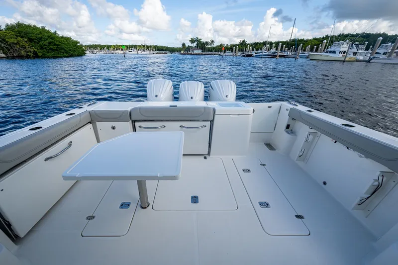  Yacht Photos Pics 2022 Pursuit OS 355 Offshore boat deck with seating, table, and scenic marina view.