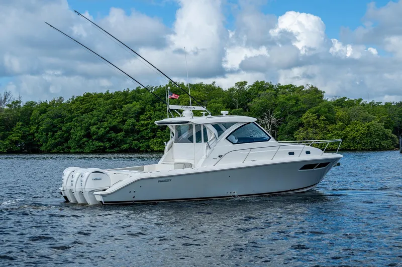  Yacht Photos Pics 2022 Pursuit OS 355 Offshore boat cruising on a scenic waterway with lush greenery.