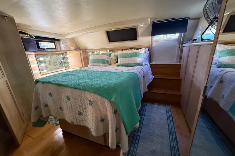 La Vie Dansante Yacht Photos Pics Luxurious bedroom in 1991 Californian 55 Cockpit Motor Yacht with teal bedding and wood accents.