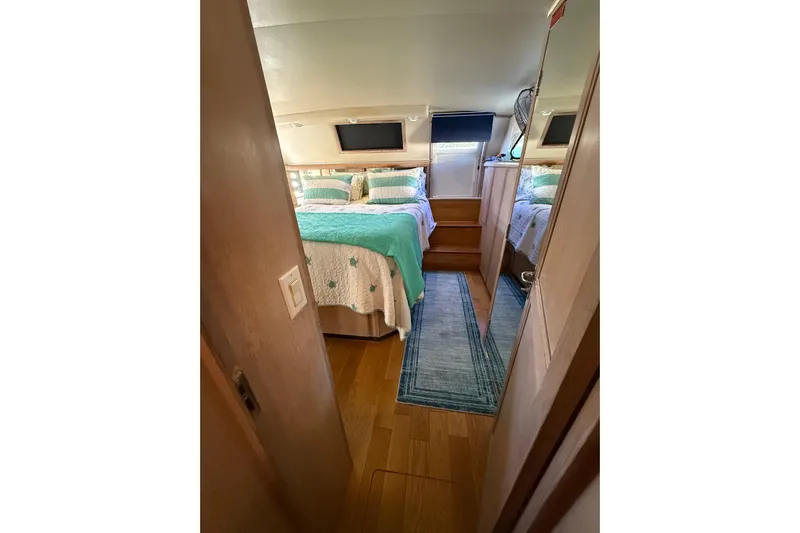 La Vie Dansante Yacht Photos Pics 1991 Californian 55 Cockpit Motor Yacht bedroom with cozy bedding and wooden flooring.