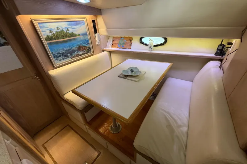 La Vie Dansante Yacht Photos Pics Cozy dining area in 1991 Californian 55 Cockpit Motor Yacht with artwork and porthole.