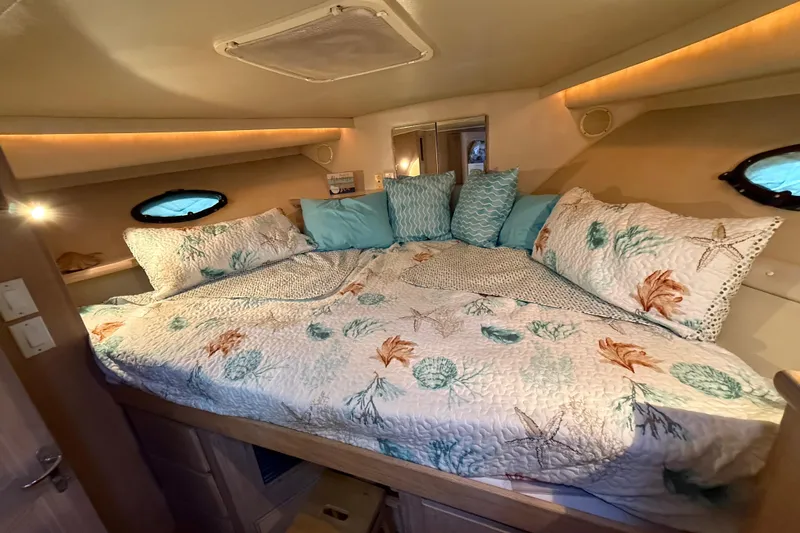 La Vie Dansante Yacht Photos Pics Cozy bedroom in 1991 Californian 55 Cockpit Motor Yacht with nautical-themed bedding.