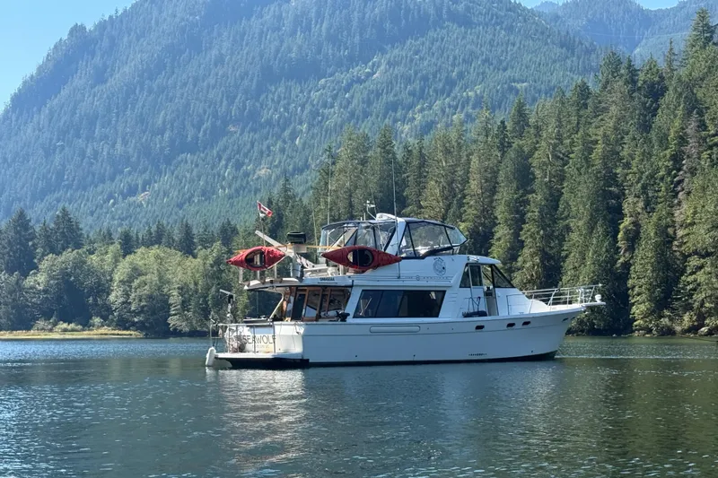 Sea Wolf Yacht Photos Pics 1994 Bayliner 4788 Pilot House Motoryacht on serene lake with forested mountain backdrop.