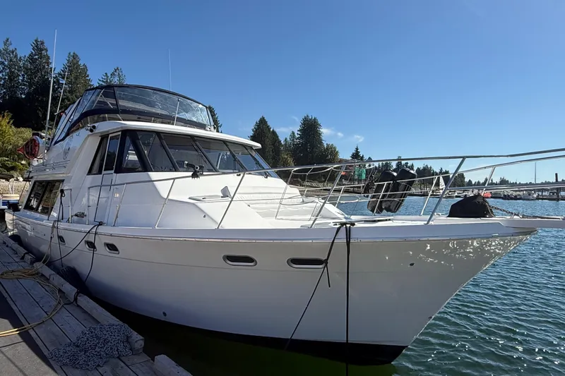 Sea Wolf Yacht Photos Pics 1994 Bayliner 4788 Pilot House Motoryacht docked by a scenic waterfront.