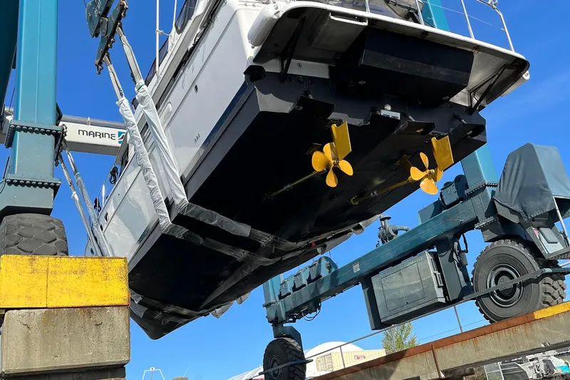 Sea Wolf Yacht Photos Pics 1994 Bayliner 4788 Pilot House Motoryacht lifted by marine crane, showcasing propellers.