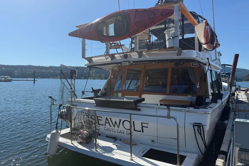 Sea Wolf Yacht Photos Pics 1994 Bayliner 4788 Pilot House Motoryacht docked, featuring kayaks on top, sunny day.