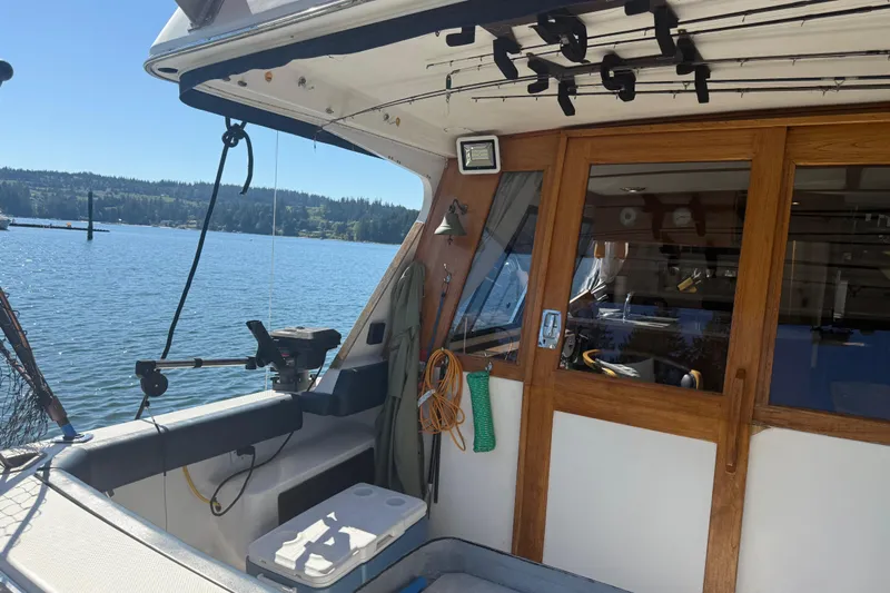 Sea Wolf Yacht Photos Pics 1994 Bayliner 4788 Pilot House Motoryacht docked, featuring fishing gear and wooden cabin doors.