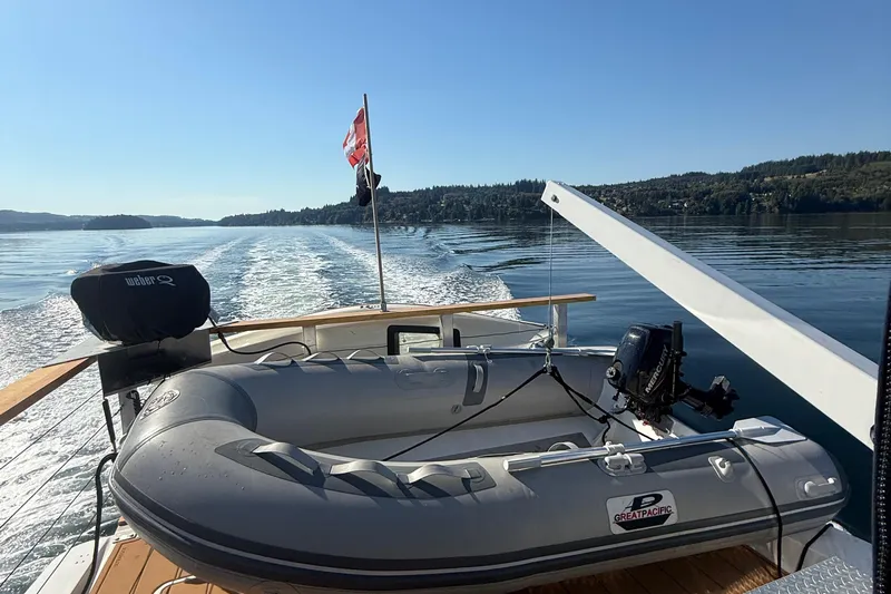 Sea Wolf Yacht Photos Pics 1994 Bayliner 4788 Pilot House Motoryacht with inflatable boat on calm water.