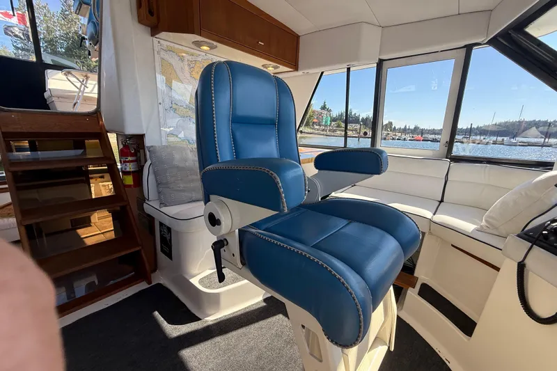 Sea Wolf Yacht Photos Pics 1994 Bayliner 4788 Pilot House Motoryacht interior with blue captain's chair and scenic window view.
