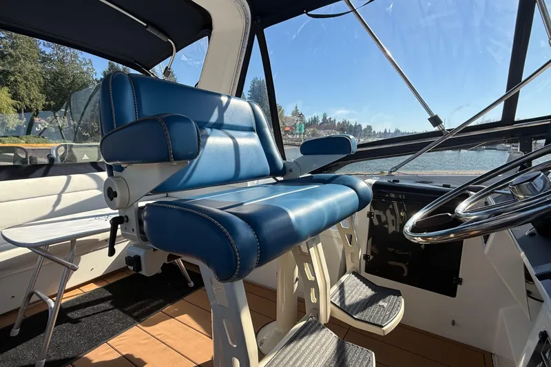 Sea Wolf Yacht Photos Pics 1994 Bayliner 4788 Pilot House Motoryacht helm with blue captain's chair and steering wheel.