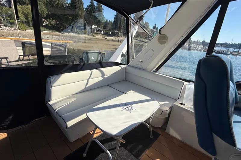 Sea Wolf Yacht Photos Pics 1994 Bayliner 4788 Pilot House Motoryacht interior with white seating and table, marina view.