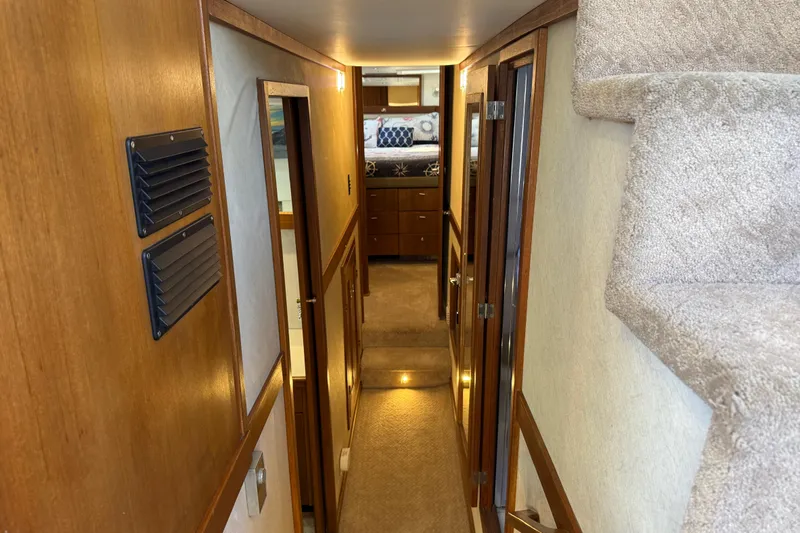 Sea Wolf Yacht Photos Pics Interior hallway of 1994 Bayliner 4788 Pilot House Motoryacht, featuring wood paneling and carpeted stairs.