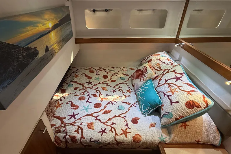 Sea Wolf Yacht Photos Pics Cozy bedroom in 1994 Bayliner 4788 Pilot House Motoryacht with nautical-themed bedding.