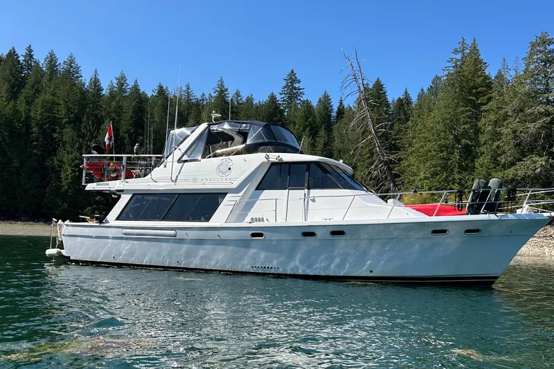 Sea Wolf Yacht Photos Pics 1994 Bayliner 4788 Pilot House Motoryacht on serene lake with forest backdrop.