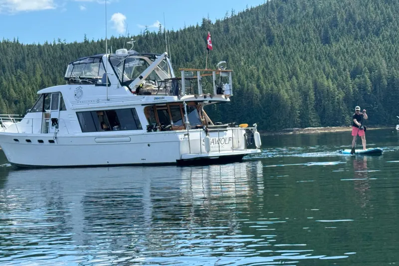 Sea Wolf Yacht Photos Pics 1994 Bayliner 4788 Pilot House Motoryacht on serene lake with paddleboarder nearby.
