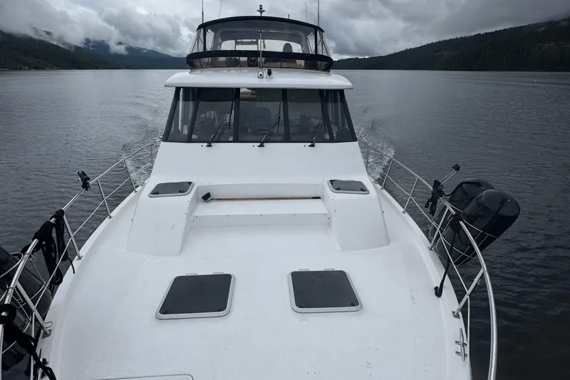 Sea Wolf Yacht Photos Pics 1994 Bayliner 4788 Pilot House Motoryacht cruising on a calm lake under cloudy skies.