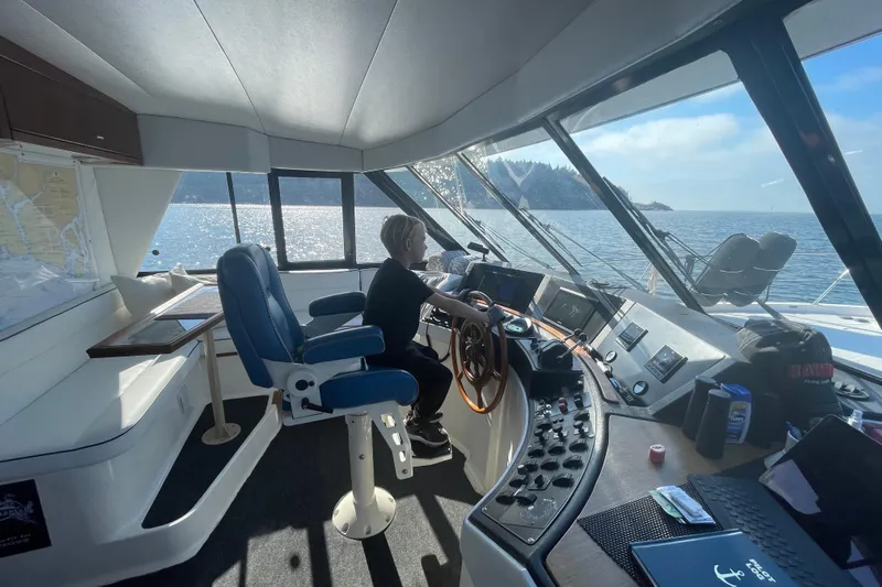 Sea Wolf Yacht Photos Pics 1994 Bayliner 4788 Pilot House Motoryacht interior with person steering, ocean view.