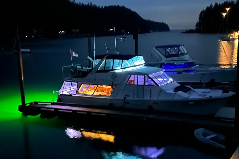 Sea Wolf Yacht Photos Pics 1994 Bayliner 4788 Pilot House Motoryacht docked at night with vibrant underwater lights.