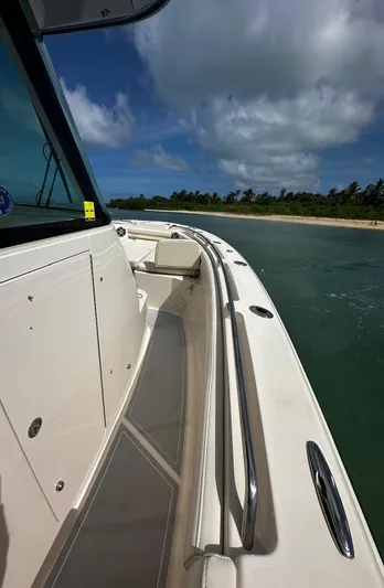  Yacht Photos Pics 2021 Grady-White Canyon 336 boat cruising near a tropical shoreline under a blue sky.