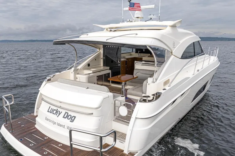 Lucky Dog Yacht Photos Pics 2018 Riviera 4800 Sport Yacht on water, rear view, "Lucky Dog" name visible.