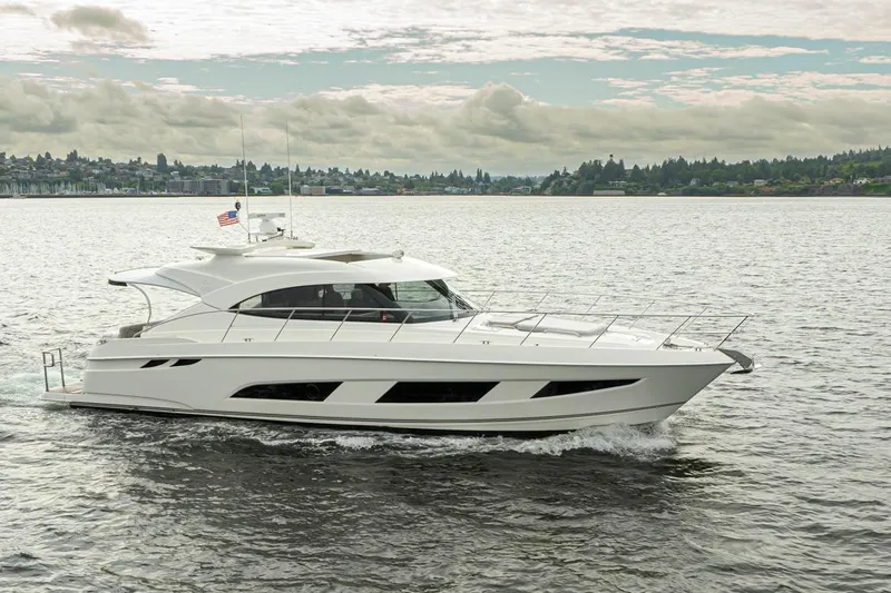 Lucky Dog Yacht Photos Pics 2018 Riviera 4800 Sport Yacht cruising on a scenic lake under cloudy skies.