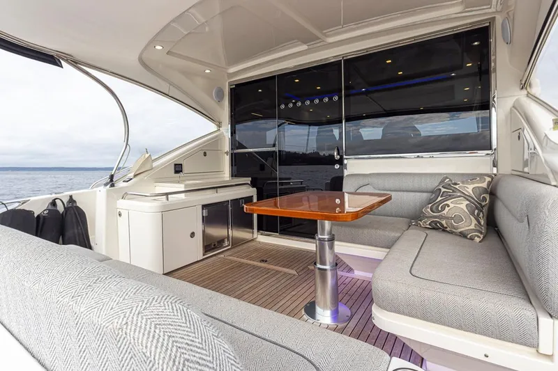 Lucky Dog Yacht Photos Pics 2018 Riviera 4800 Sport Yacht interior with elegant seating and wooden table, overlooking the ocean.