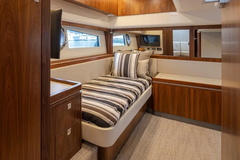 Lucky Dog Yacht Photos Pics Luxurious cabin interior of 2018 Riviera 4800 Sport Yacht with wood finish and striped bedding.