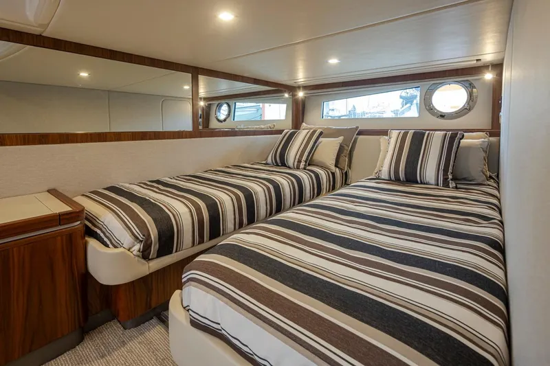 Lucky Dog Yacht Photos Pics 2018 Riviera 4800 Sport Yacht cabin with twin beds and striped bedding.