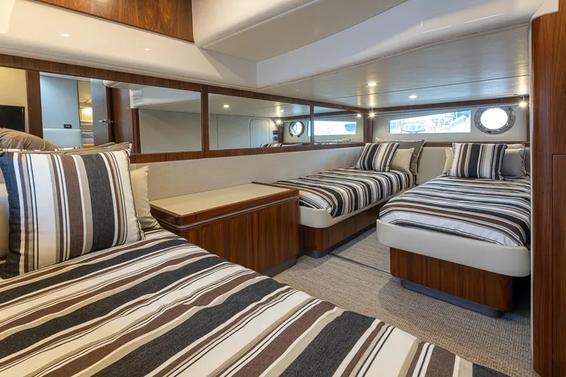 Lucky Dog Yacht Photos Pics Luxurious interior of 2018 Riviera 4800 Sport Yacht with striped bedding and elegant wood finishes.