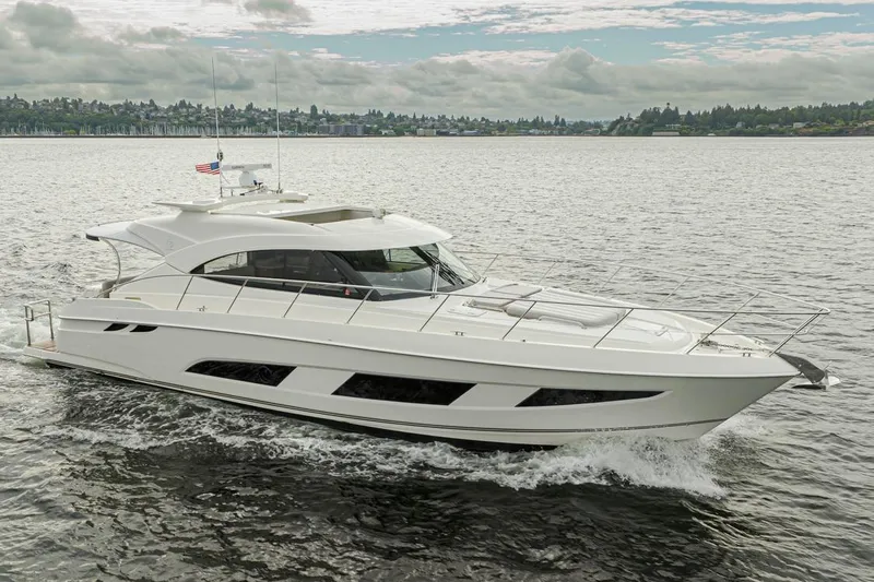 Lucky Dog Yacht Photos Pics 2018 Riviera 4800 Sport Yacht cruising on a scenic lake under a cloudy sky.