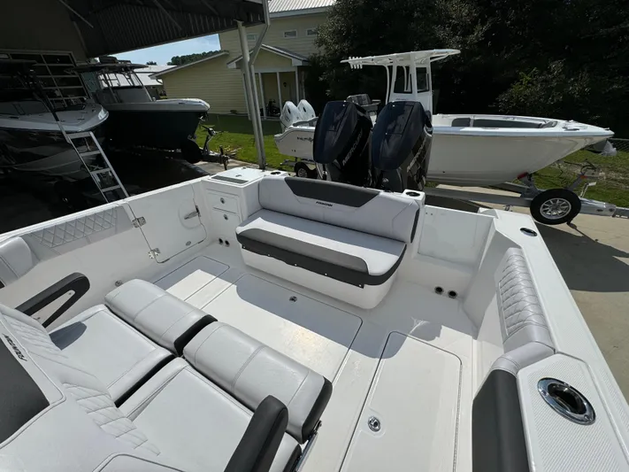  Yacht Photos Pics 2024 Fountain 32 NX boat interior with seating and dual engines in a marina setting.