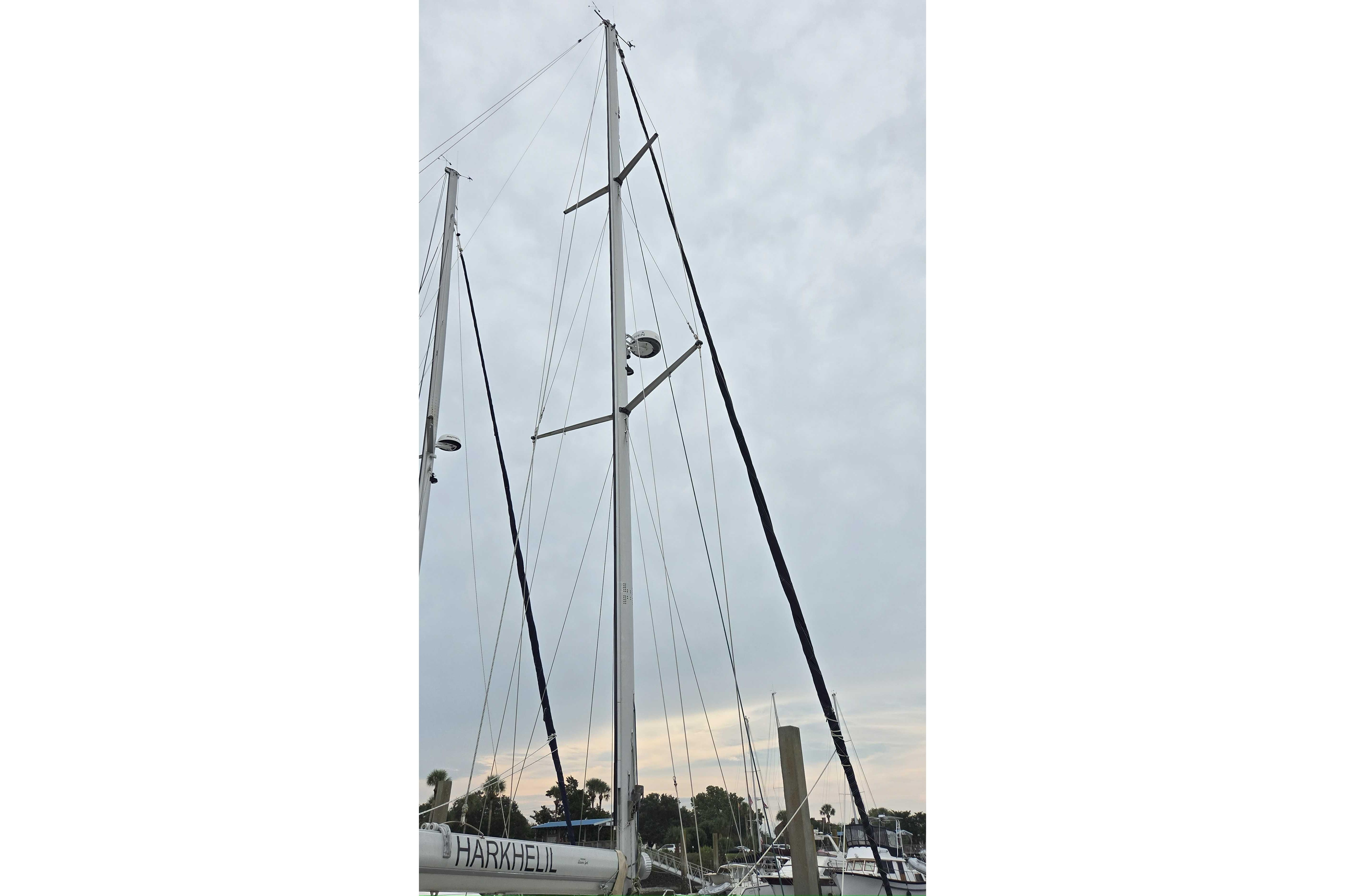 Mast of 2001 Caliber 40LRC sailboat against cloudy sky in marina.