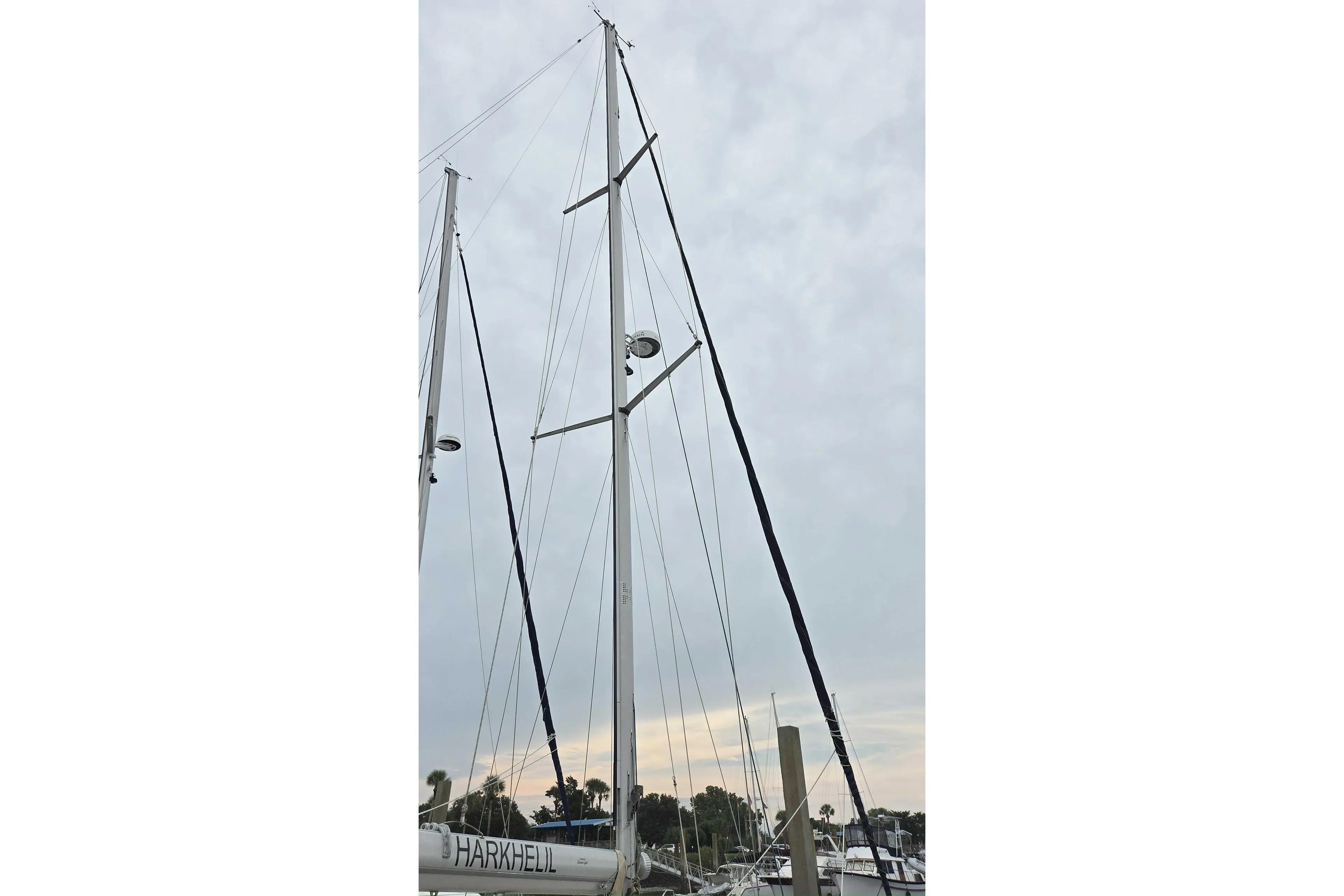 Mast of 2001 Caliber 40LRC sailboat against cloudy sky in marina.