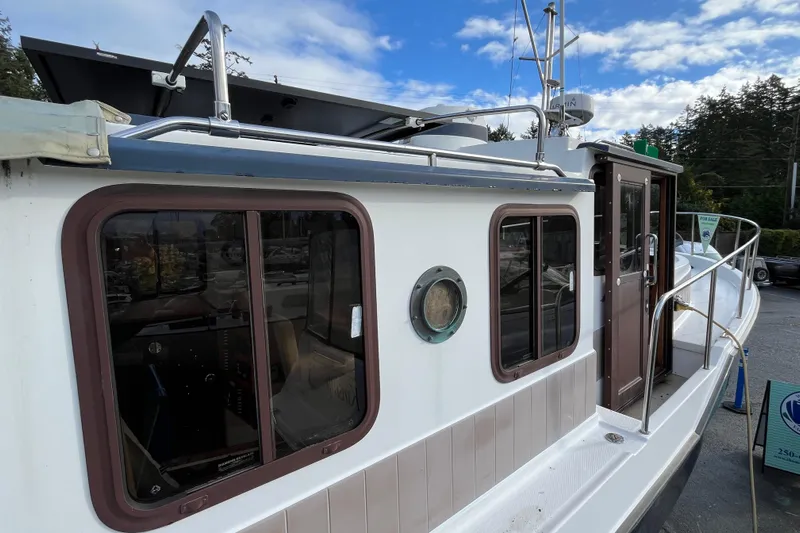 Rockin' Robin Yacht Photos Pics 2009 Ranger Tugs R-29 boat exterior with windows and railing under a blue sky.
