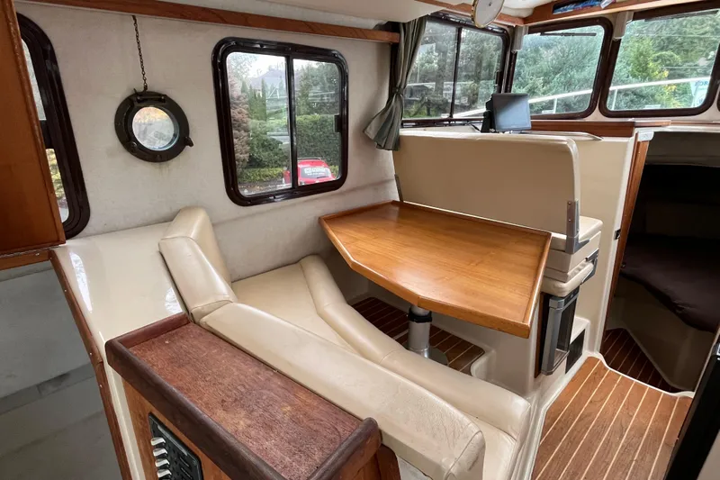 Rockin' Robin Yacht Photos Pics Interior of 2009 Ranger Tugs R-29 with wooden table and seating, featuring large windows.