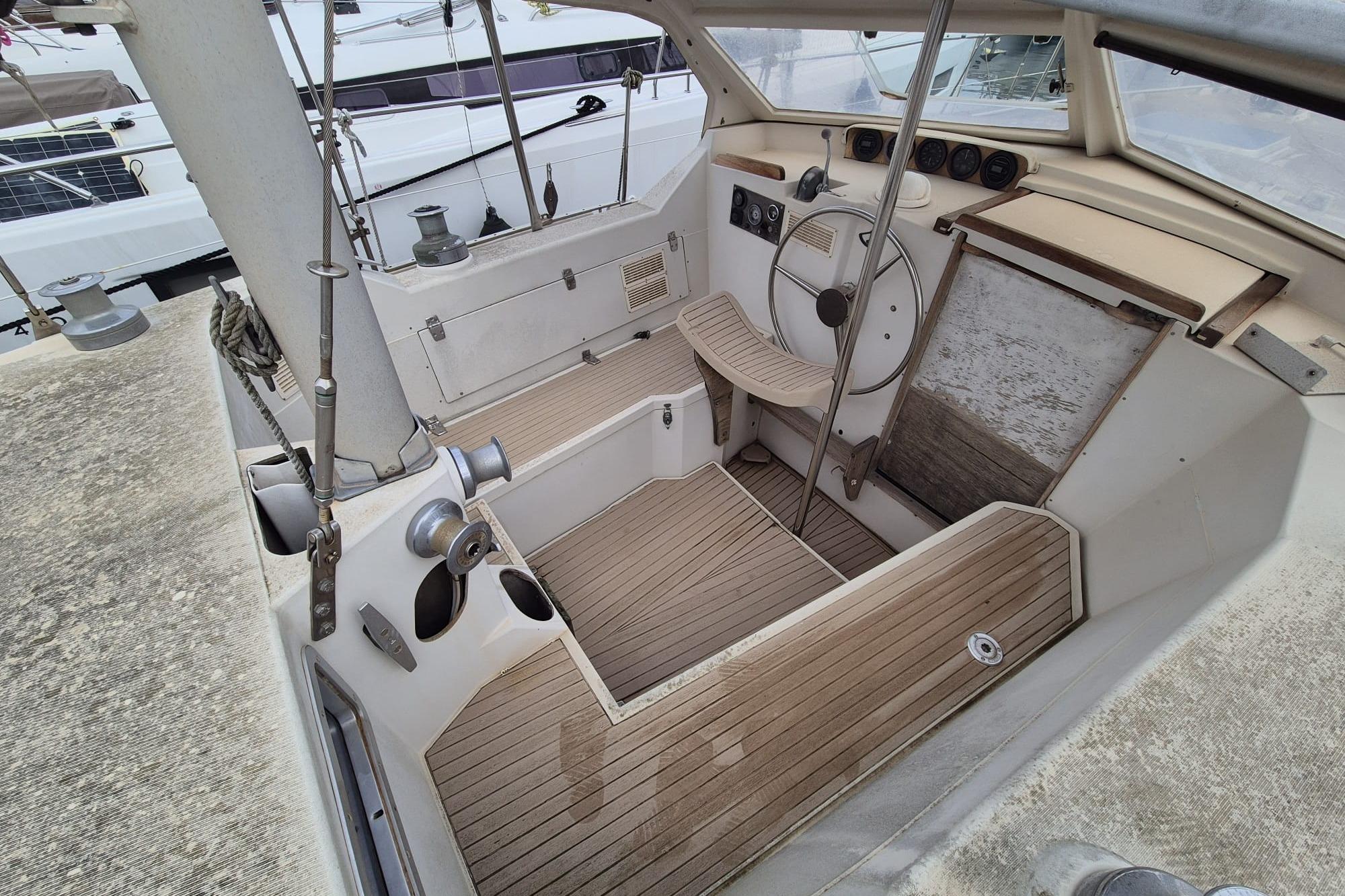 1980 Amel Sharki sailboat cockpit with wooden flooring and steering wheel.