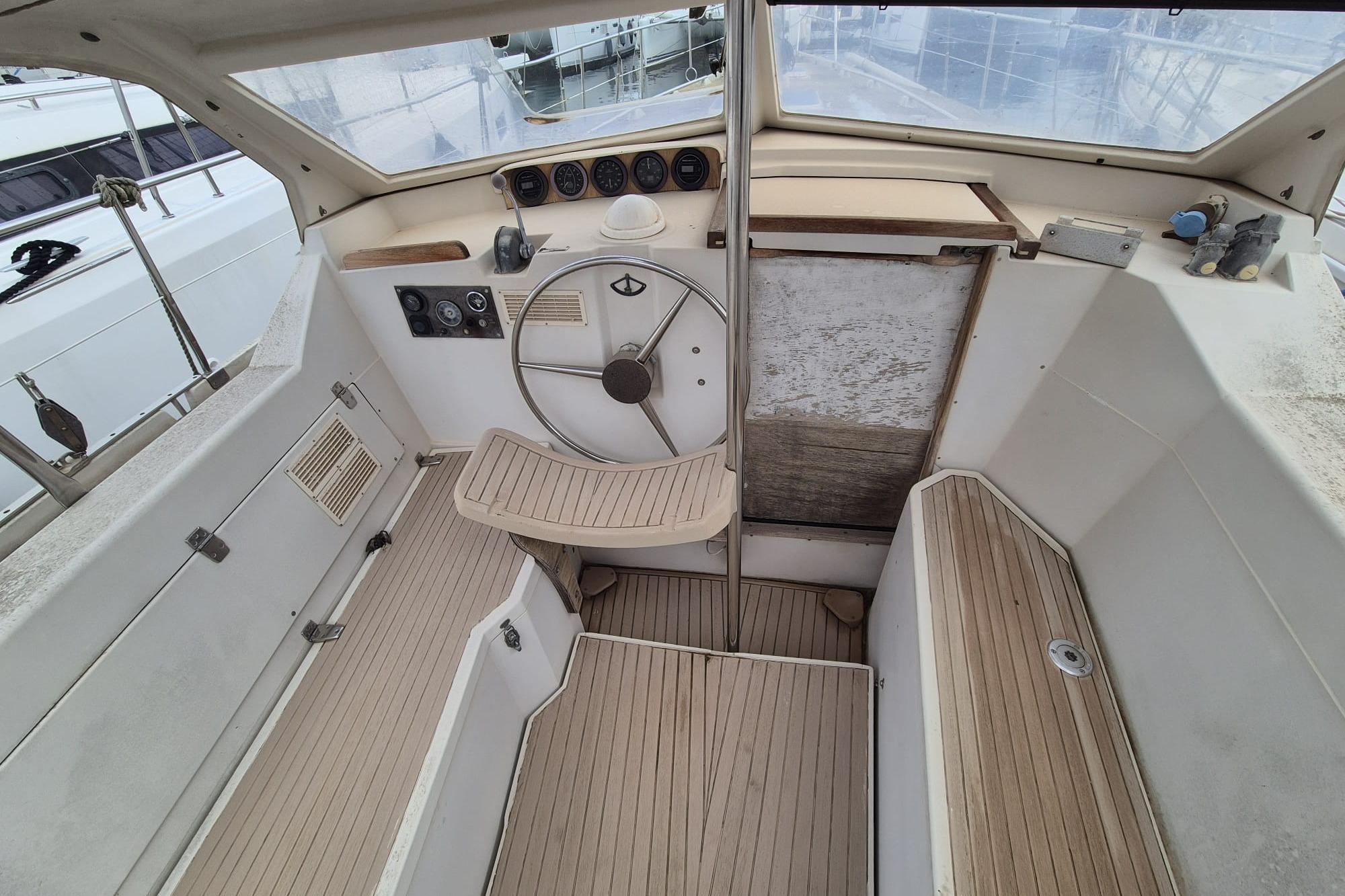 1980 Amel Sharki boat cockpit with wooden flooring and steering wheel.