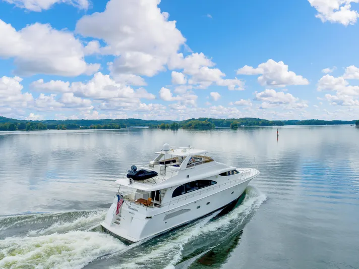 Marvelous Yacht Photos Pics Luxurious 1999 Cheoy Lee 74 yacht cruising on a serene lake under a blue sky.