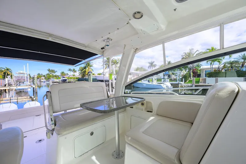 F-troop Yacht Photos Pics 2017 Boston Whaler 345 Conquest interior with seating and table, docked by palm trees.