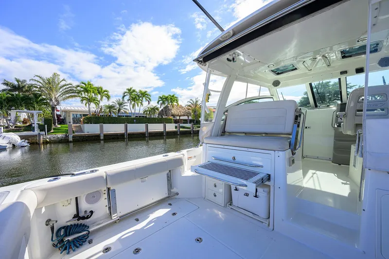 F-troop Yacht Photos Pics 2017 Boston Whaler 345 Conquest boat interior with seating, docked by palm trees.