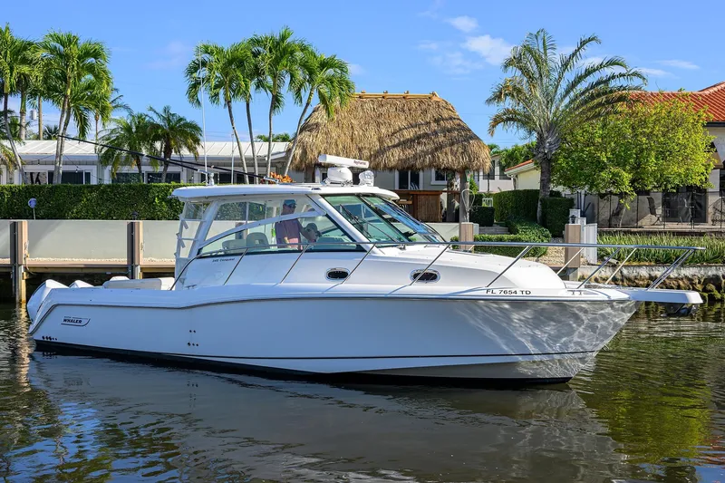 F-troop Yacht Photos Pics 2017 Boston Whaler 345 Conquest boat on a calm waterway, surrounded by tropical scenery.