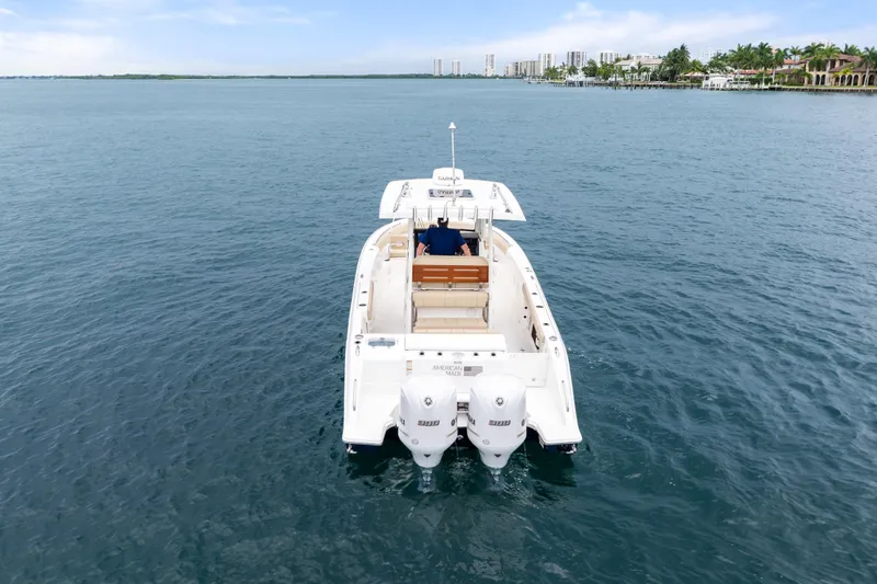 Little Perspective Yacht Photos Pics 2019 Pursuit S 288 Sport boat cruising on open water, city skyline in background.