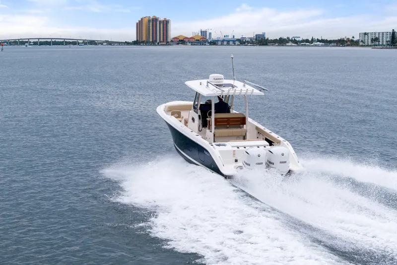 Little Perspective Yacht Photos Pics 2019 Pursuit S 288 Sport boat cruising on open water, cityscape in background.
