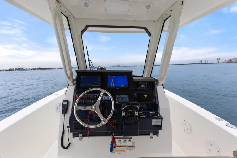 Little Perspective Yacht Photos Pics 2019 Pursuit S 288 Sport boat helm with navigation screens, steering wheel, and ocean view.