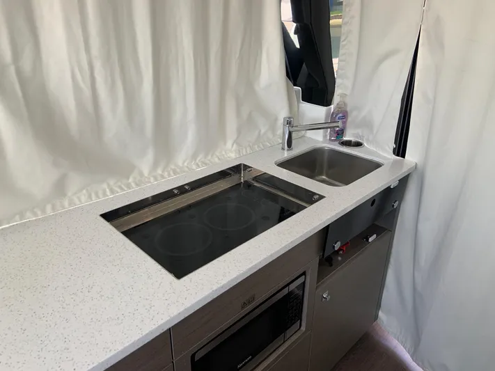  Yacht Photos Pics Compact kitchen in 2025 Jeanneau NC 1095 Coupe with sink and induction cooktop.