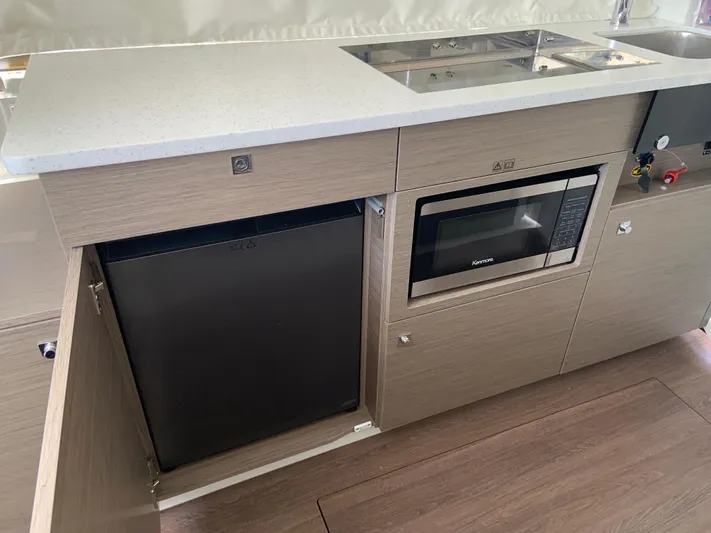  Yacht Photos Pics Modern kitchen area in 2025 Jeanneau NC 1095 Coupe with microwave and compact fridge.